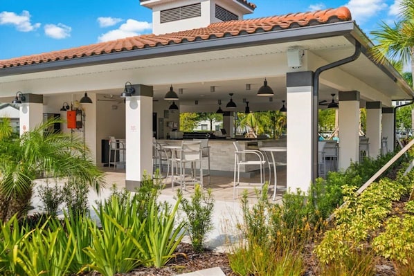 An outdoor patio area with a covered seating area, a water feature, and a variety of plants. - Vista Cay - 28800 (Orlando)