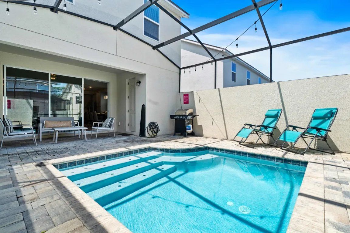 A swimming pool with lounge chairs and a covered patio area.
