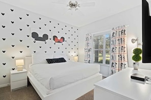 A bedroom with a bed, a nightstand, a desk, a ceiling fan, and a window with curtains. - Paradise Palms - 29166 (Kissimmee)