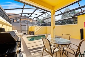 An outdoor patio with a grill, pool, and seating area. - Paradise Palms - 29166 (Kissimmee)