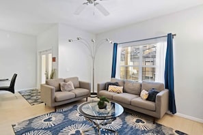 A modern living room with two sofas, a coffee table, a floor lamp, and a large window with curtains. - Paradise Palms - 29166 (Kissimmee)