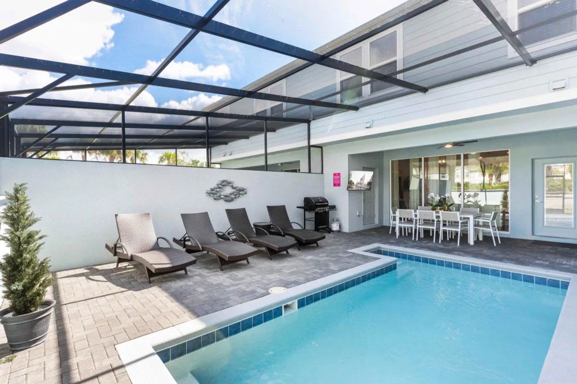 A pool area with lounge chairs and a barbecue grill.