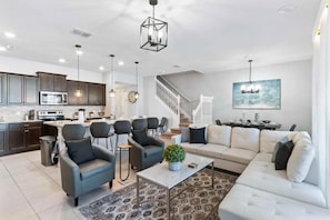 A modern kitchen with dark cabinets, a central island, and a dining area with chairs. - Windsor Island - 29337 (Davenport)