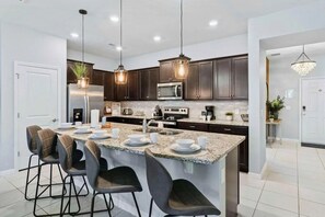A modern kitchen with dark wood cabinets, stainless steel appliances, and a central island with bar stools. - Windsor Island - 29337 (Davenport)