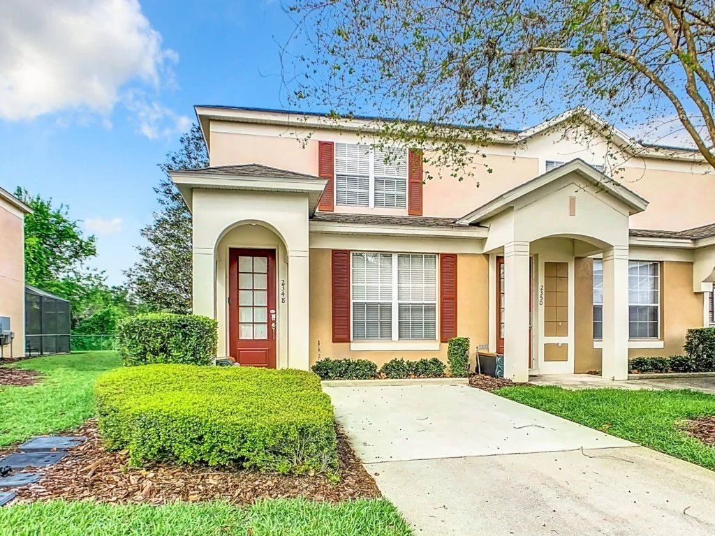A two-story residential house with a front entrance, a driveway, and a well-maintained lawn.