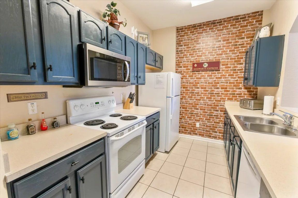 Une cuisine avec un mur en briques, un four à micro-ondes, une cuisinière, un réfrigérateur et un évier.