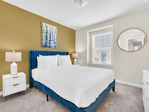 A bedroom with a bed, bedside tables, a window with blinds, a wall-mounted mirror, and a painting. - Windsor Island - 33034 (Davenport)