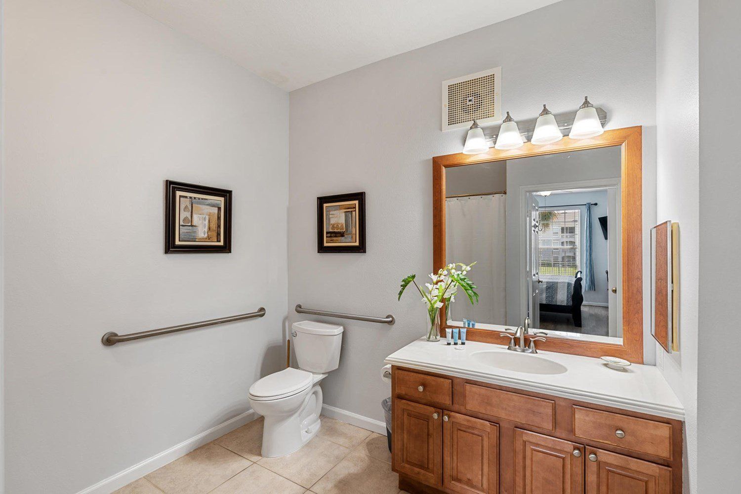 A bathroom with a toilet, vanity, and a large mirror.