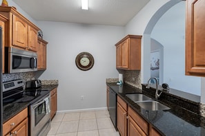 A kitchen with wooden cabinets, a microwave, a stove, and a sink. - Windsor Palms - 34815 (Kissimmee)