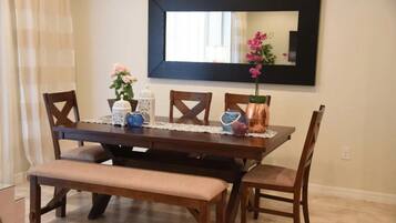 A dining area with a dark wooden table, four chairs, a bench, and a large mirror on the wall.