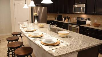 A modern kitchen with granite countertops, stainless steel appliances, and bar stools.