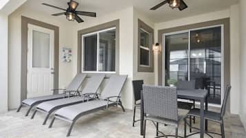 A sunroom with a ceiling fan, a table with chairs, and a window with blinds.