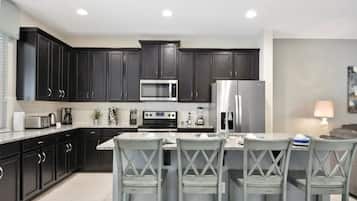 A modern kitchen with dark cabinets, stainless appliances, and a central island with bar stools.