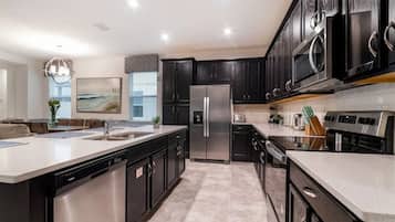 A modern kitchen with a central island, stainless steel appliances, and dark cabinetry.