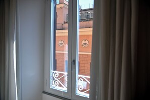 A window with a metal balcony railing and a view of a brick building with circular decorations. - Three steps from Spanish Steps, Via Veneto, and Villa Borghese (ROMA - RM)