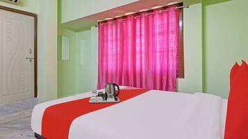 Habitació d'hotel amb un llit, una finestra amb cortines roses, aire condicionat fixat a la paret i una porta amb mànega.