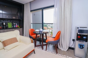 A modern hotel room with a sofa, two chairs, a small table, a water dispenser, and a view of the city through a large window. - Cozy & Stylish Studio (Nairobi)