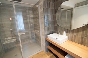 A modern bathroom with a glass-enclosed shower, a wooden vanity, and a large mirror. - Charming Catania Apartment With Balcony (Catania)