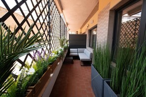 A balcony with a seating area, potted plants, and a view of the street. - Charming Catania Apartment With Balcony (Catania)