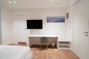 A bedroom with a bed, a desk, a chair, a TV, and a painting on the wall. - Charming Catania Apartment With Balcony (Catania)