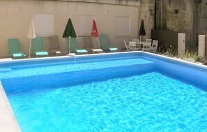 Ein Schwimmbecken mit Liegestühlen und Sonnenschirmen.