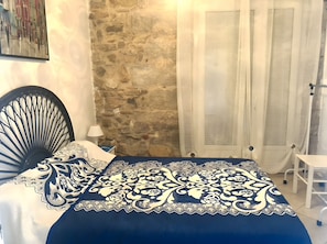 Ein Zimmer mit einem Bett, einer Steinsäule und einer mit Vorhängen versehenen Tür.