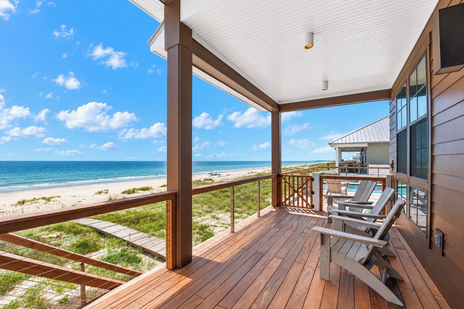 A wooden deck with a view of the beach and ocean.