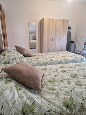 A bedroom with two beds, each with a floral-patterned bedspread and two pillows.