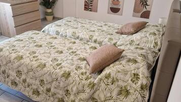 A bedroom with a bed, a bedside table, a chair, and a wall with three artworks.