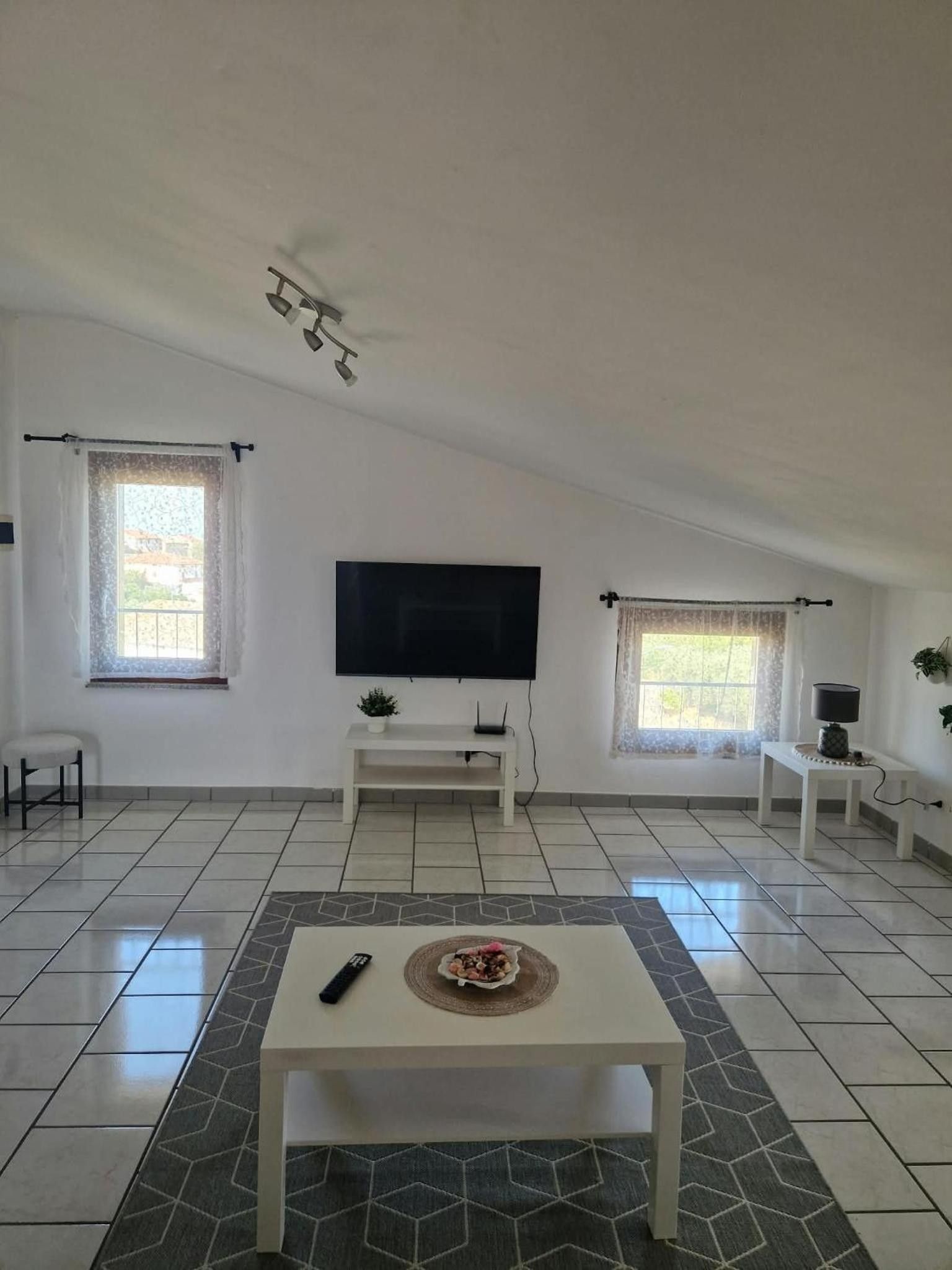 A spacious living room with a flat-screen TV, a coffee table, and a dining area with a table and chairs.