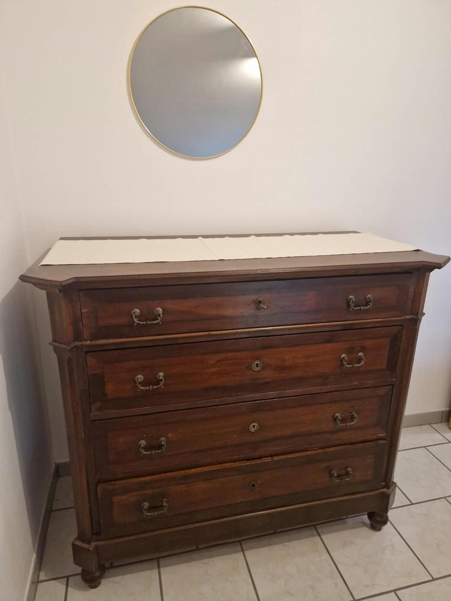A dark wooden dresser with multiple drawers and a round mirror above it.