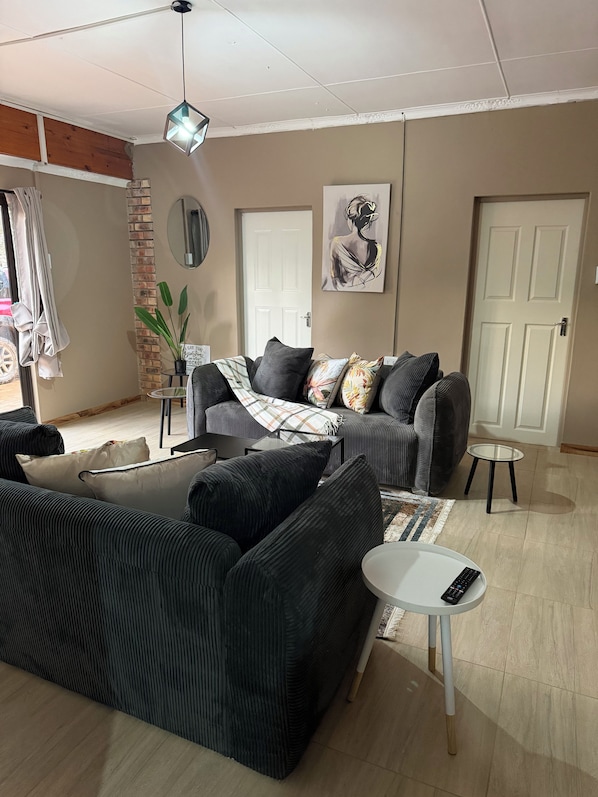 A living room with a sofa, a coffee table, a small side table, and a hanging light fixture.