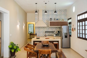A modern kitchen with a central island, pendant lighting, and patterned backsplash. - Casa Grande 5 Blocks to Montejo (Mérida)