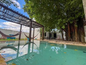 A swimming pool with a pergola and hammocks, surrounded by trees and a white building. - Casa Grande 5 Blocks to Montejo (Mérida)