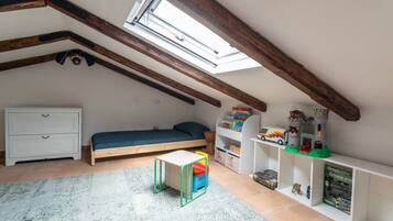 A child's bedroom with a bunk bed, a small table, and shelves with toys and books.