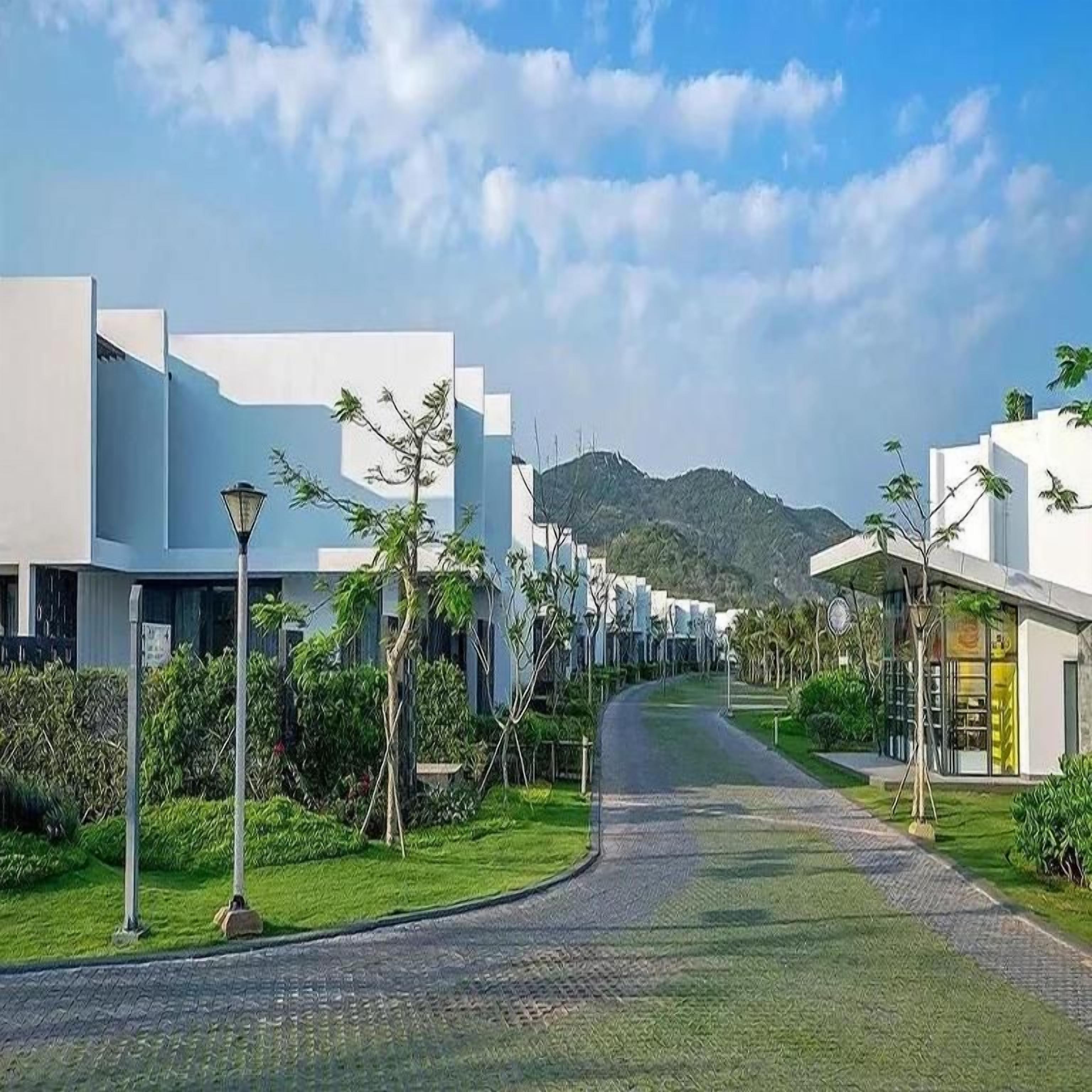 A pathway leading to modern buildings with a mountain backdrop.