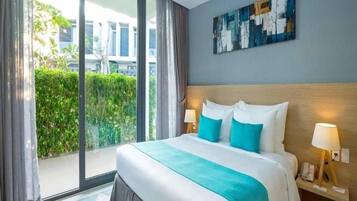 Een hotelkamer met een groot bed, uitzicht op groen en een modern abstract schilderij aan de muur.