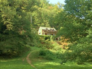 A secluded house surrounded by dense greenery, with a dirt path leading to it. - Holiday Home 'Bourdounal' with Swimming River, 2 Hectares of Private Nature, Terrace and Wi-Fi (Crespin)