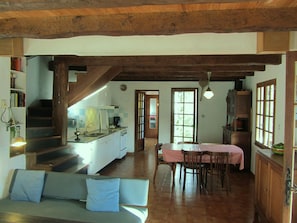 A spacious kitchen with a dining area, wooden beams, and a staircase leading to an upper level. - Holiday Home 'Bourdounal' with Swimming River, 2 Hectares of Private Nature, Terrace and Wi-Fi (Crespin)