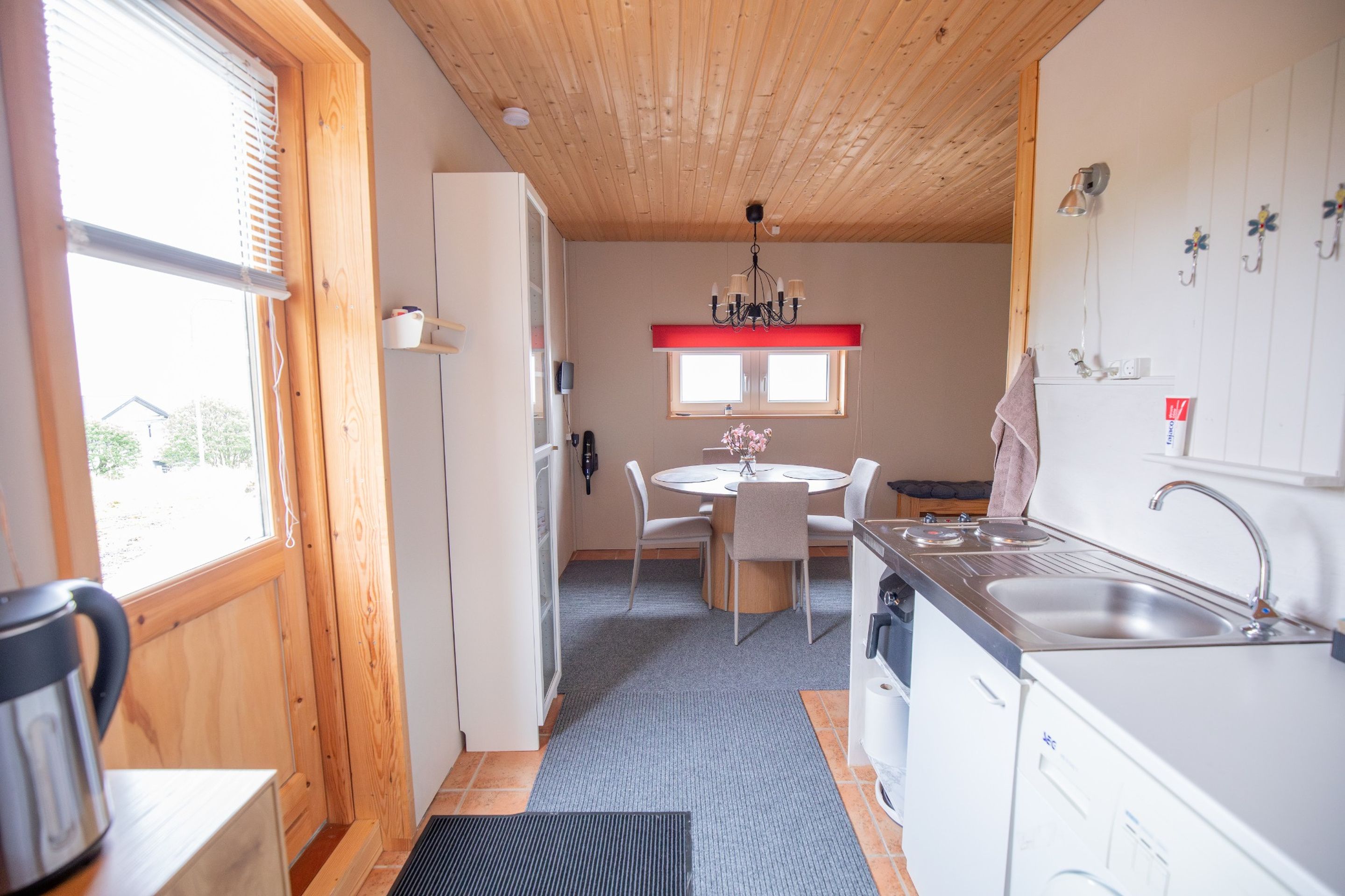 Une cuisine de taille réduite avec un coin repas, un plafond en bois et une vue par la fenêtre.