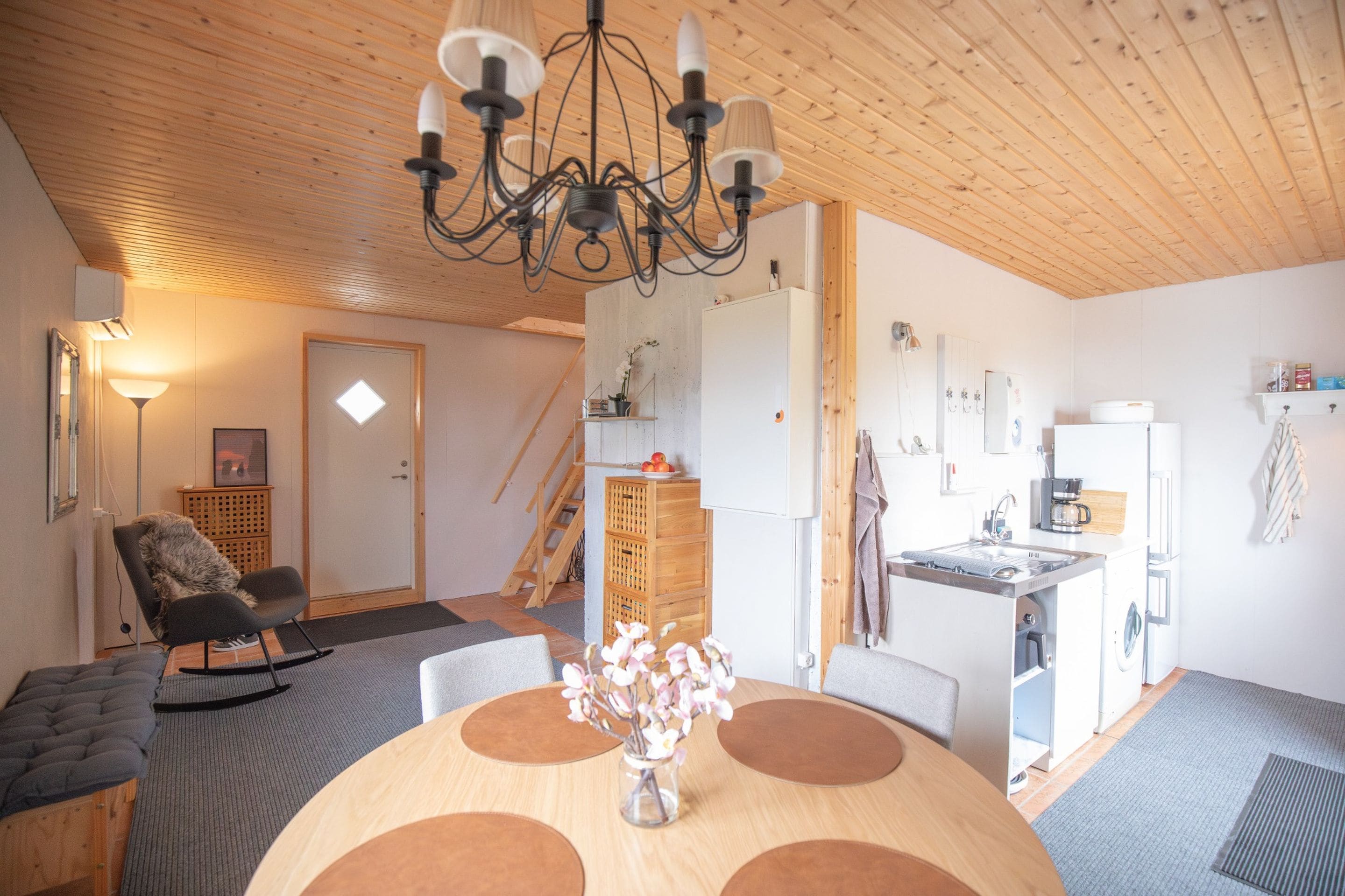 Un interior acogedor con comedor, cocina y una escalera que lleva a un nivel superior.