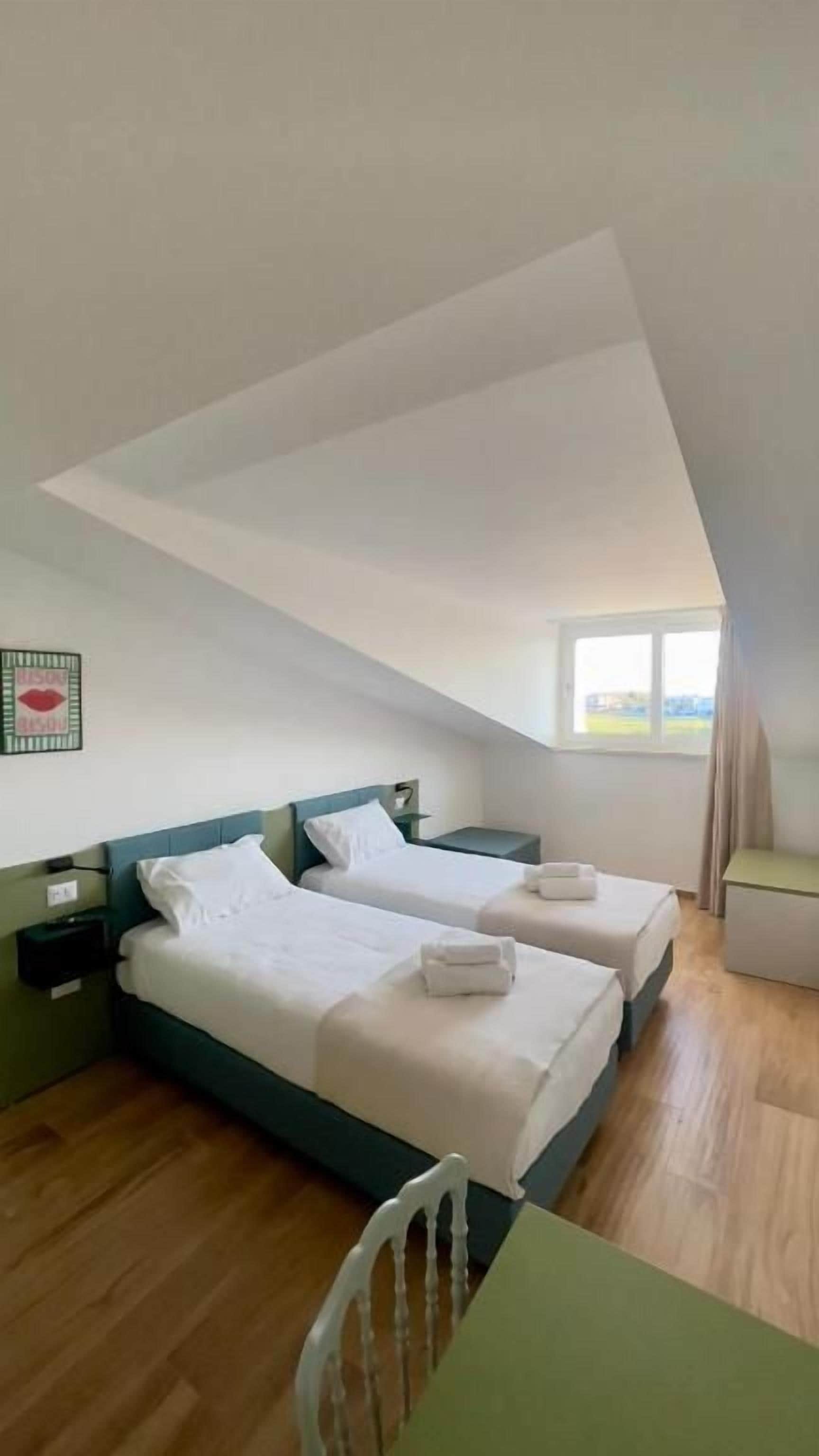 Une chambre avec deux lits, une table et une chaise.