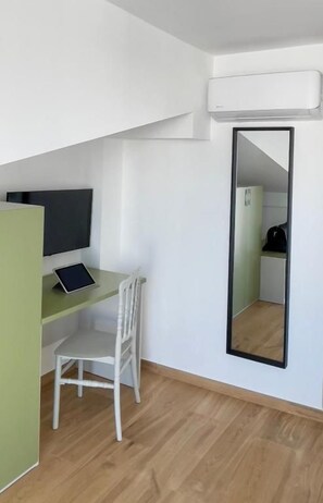 Una habitación con escritorio, silla y un espejo grande.