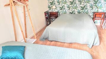 Een slaapkamer met twee bedden, een houten trap, een boekenkast en tropisch behang.
