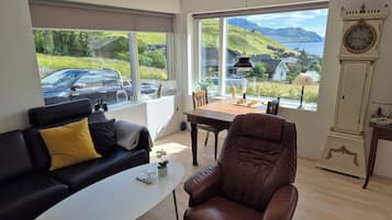 A modern living room with a sofa, armchair, coffee table, and a view of a car parked outside.