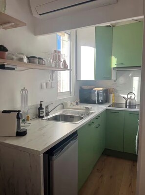 A compact kitchen with a dishwasher, a sink, and a microwave. There is a window providing natural light, and the cabinets are green. - Rooftop terrace in the heart of Aix-en-Provence (Aix-en-Provence)