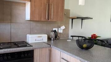 A kitchen with wooden cabinets, a countertop, a toaster, and a kettle.