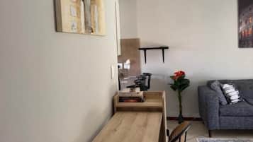 Un coin repas avec une table et des chaises en bois, un canapé gris et un tableau accroché au mur.