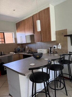 Une cuisine dotée d’un îlot central, de tabourets de bar et de meubles de rangement en bois.