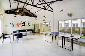 A recreational room with a pool table, ping pong table, and a mural of athletes.